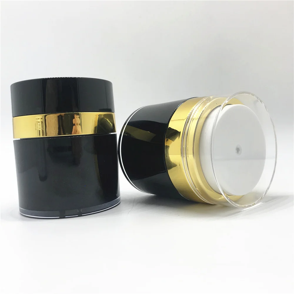 Two black cosmetic jars with gold accents and transparent lids on a white background.