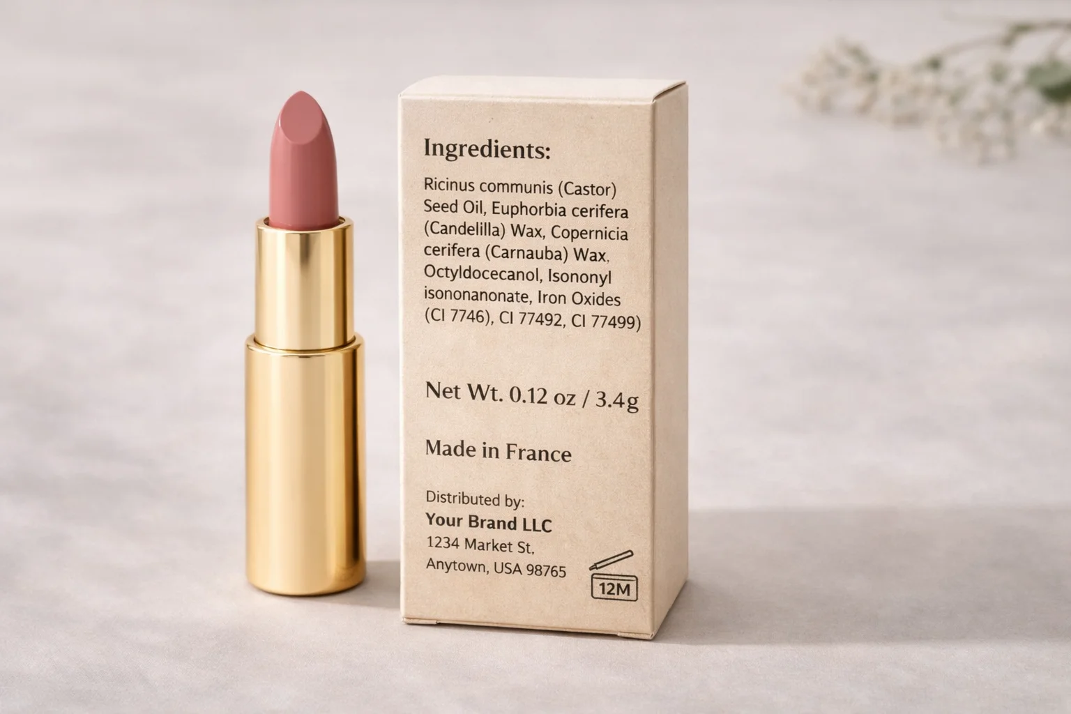 Pink lipstick in a gold tube next to its ingredient box detailing castor seed oil and waxes. Made in France, distributed by Your Brand LLC.
